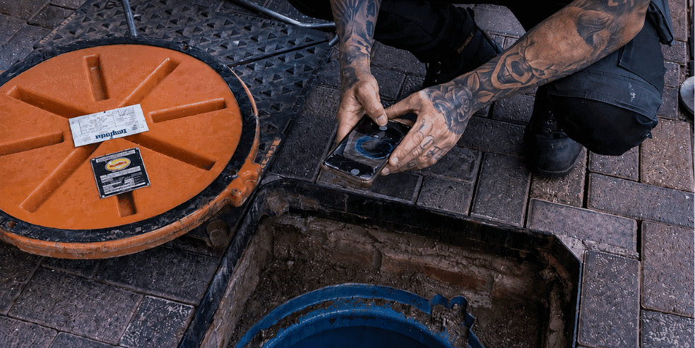 Engineer using a mobile device while inspecting a commercial grease trap